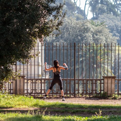 ROME, ITALY - MARCH 29 2014: Young adult woman doing stretching in the City Park of Rome on a warm spring morning on MARCH 29 2014 in Rome in Italy